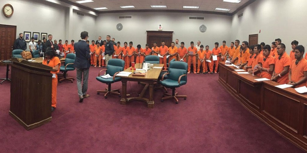 A recently leaked image shows dozens of immigrants in orange jumpsuits, their hands and feet shackled, undergoing a "mass trial" in Pecos, Texas, a small town roughly 70 miles southwest of Odessa. (Source: The Intecept via The Houston Chronicle)